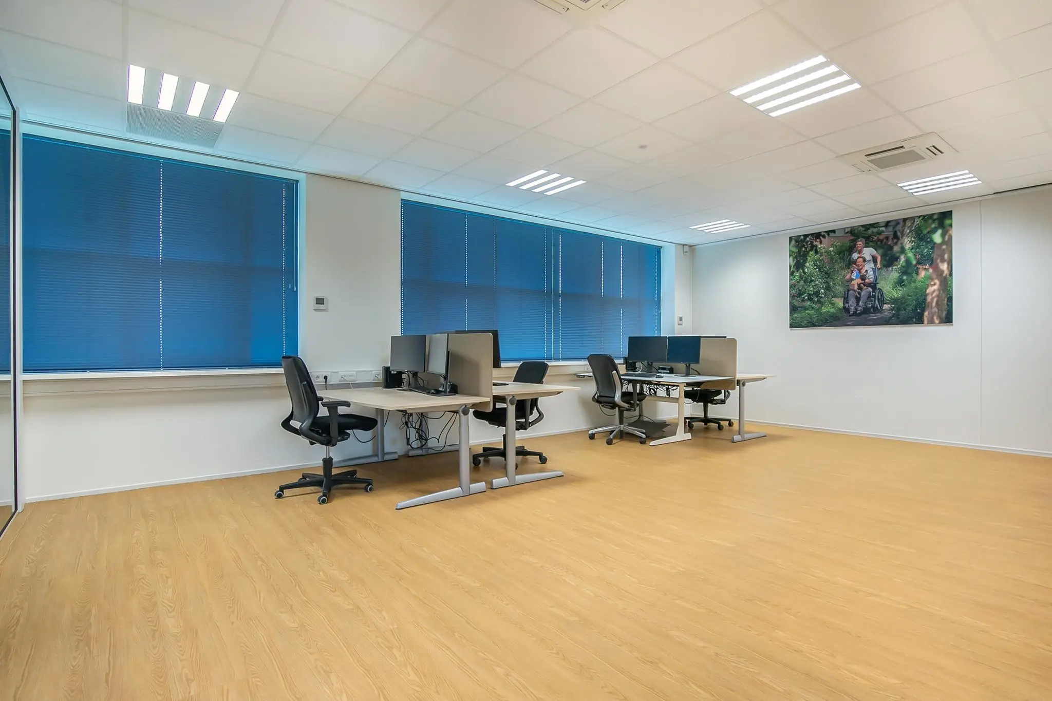 Moderne, lichte kantoorruimte aan het Rhijnspoor met meerdere werkplekken en blauwe jaloezieën.