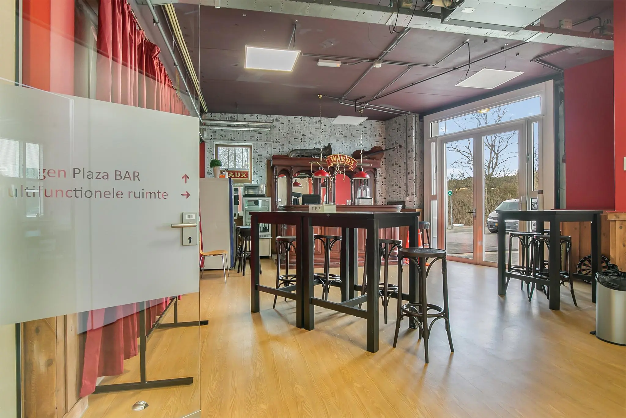 Multifunctionele ruimte in Rhijnspoor met hoge tafels, barkrukken en een bar met retro-inrichting.