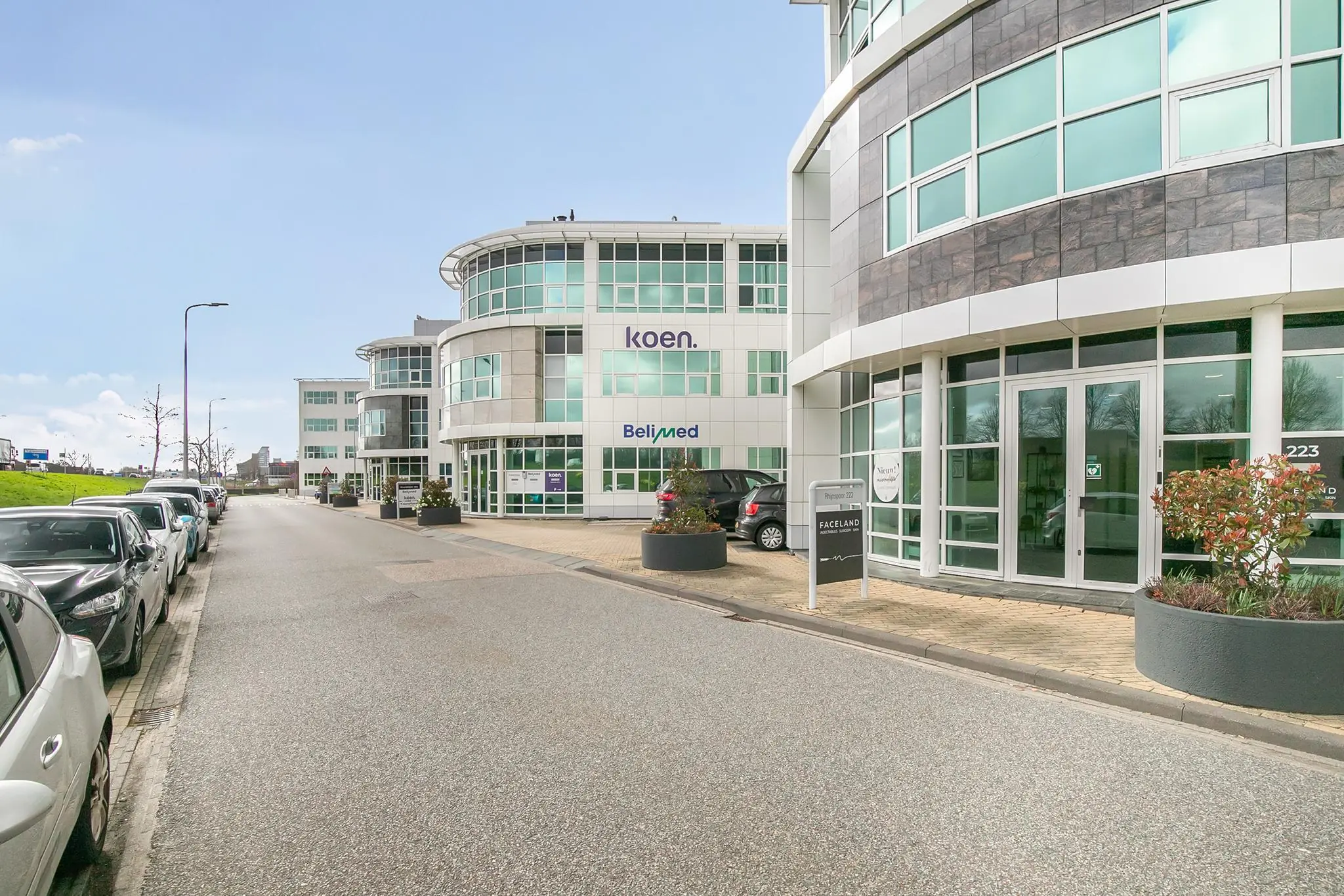 Moderne kantoorpanden aan het Rhijnspoor met bedrijfsnamen zoals Koen, Belimed en Faceland zichtbaar op de gevels.