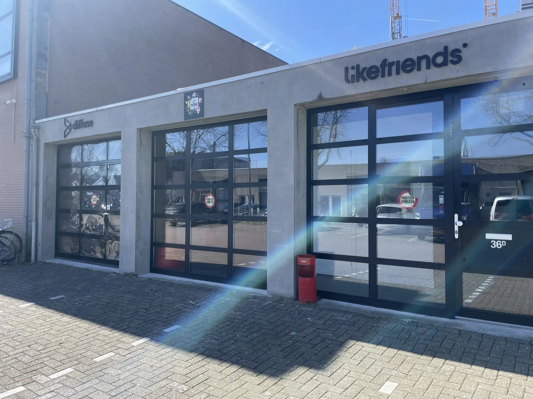 Vooraanzicht van bedrijfspand aan de Veemarkt met logo's van Likefriends en Diffuse op glazen garagedeuren.