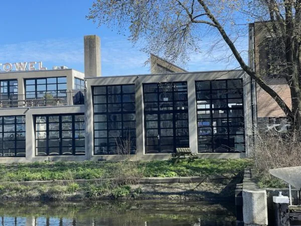 Gebouw met grote glazen ramen aan het water op het terrein van de Veemarkt in Amsterdam.