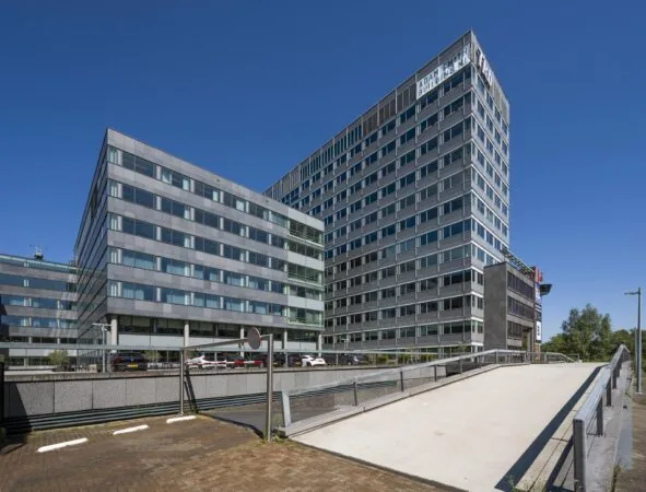 Modern kantoorgebouw aan de Thomas R. Malthusstraat in Amsterdam met glazen gevel en oprijbrug op de voorgrond.