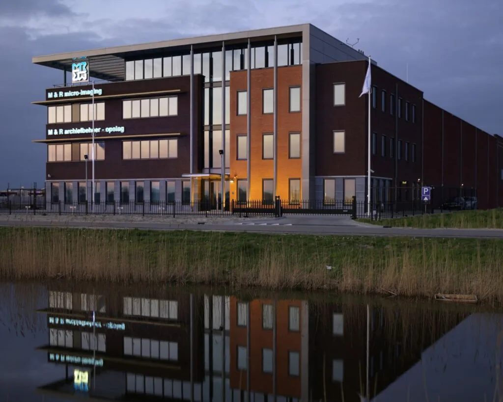 Modern kantoorgebouw aan de Carlsonstraat 13 in Kampen, weerspiegeld in het water bij schemering.