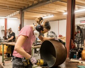 Twee vrouwen werken met beschermende uitrusting aan metaalbewerking in een werkruimte in Steiger 24, Almere.