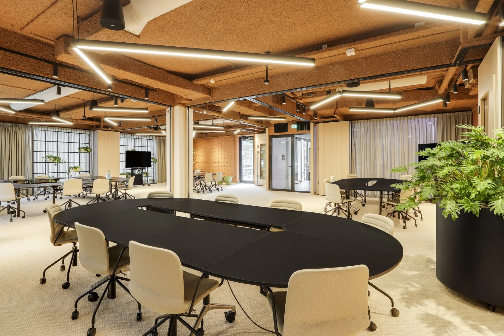 Moderne showroomruimte in Sloterdijk met flexibele werkplekken, ronde tafels en warme verlichting.