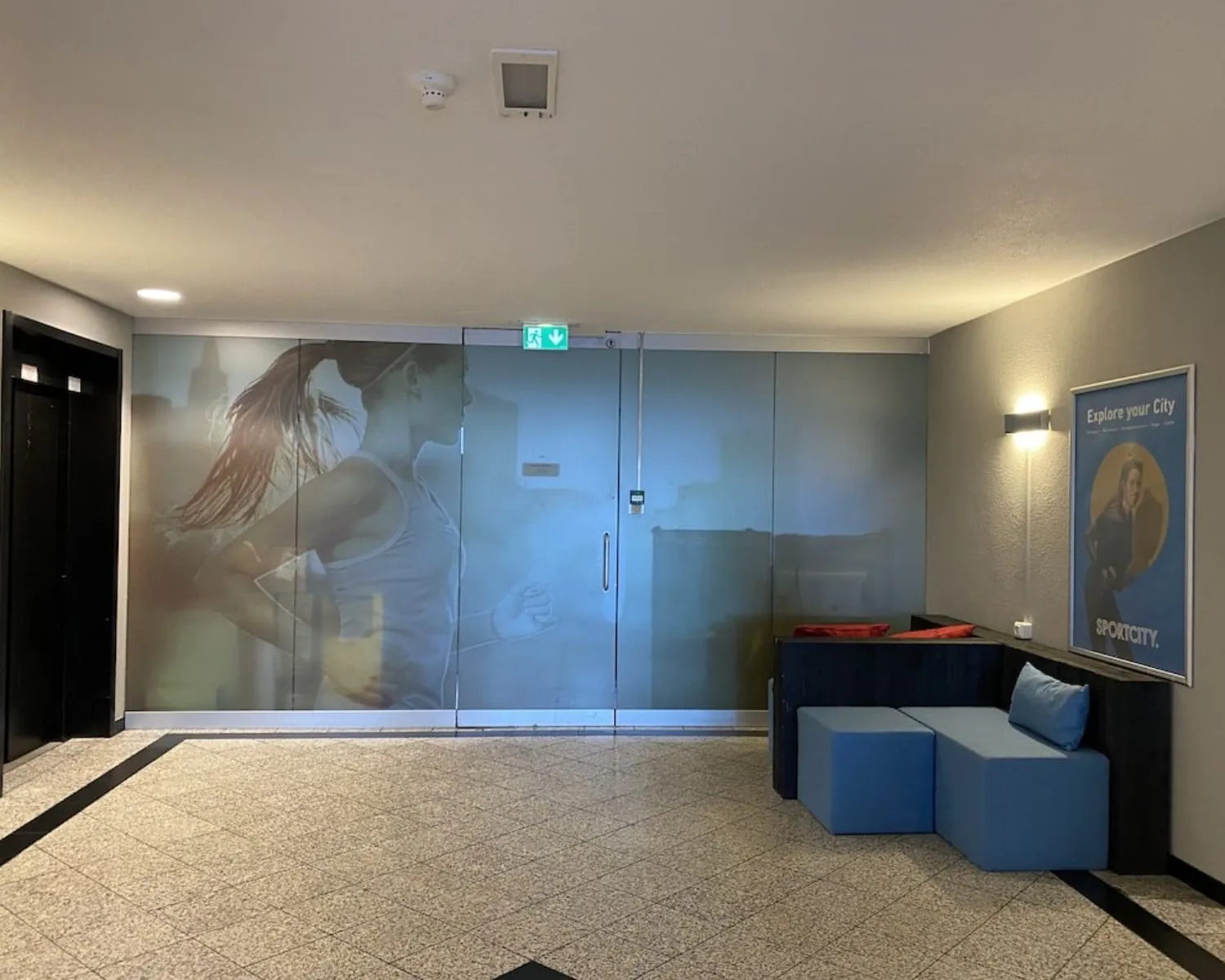 Moderne entree van kantoorruimte Elisabethhof in Leiderdorp met glazen wand met sportafbeelding en wachthoek.