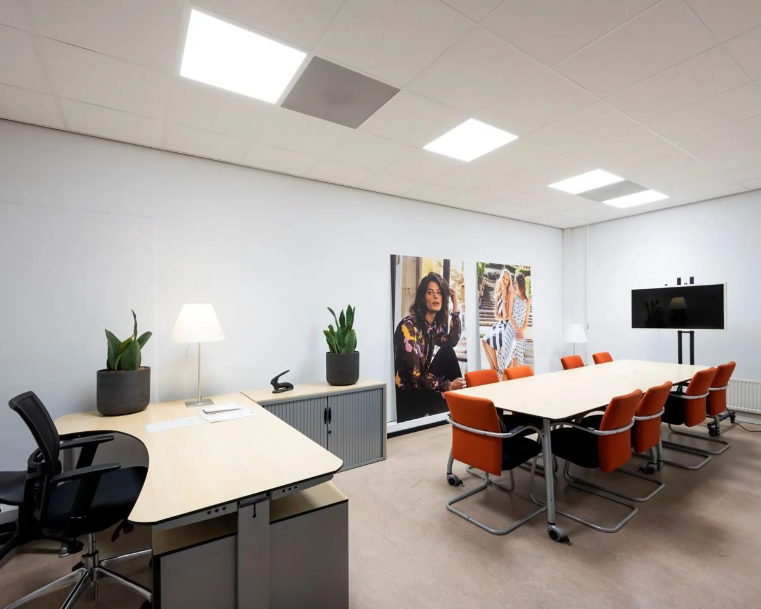 Moderne kantoorruimte in Stammerhove 1, Diemen, met vergadertafel, oranje stoelen, werkplek en wanddecoratie.