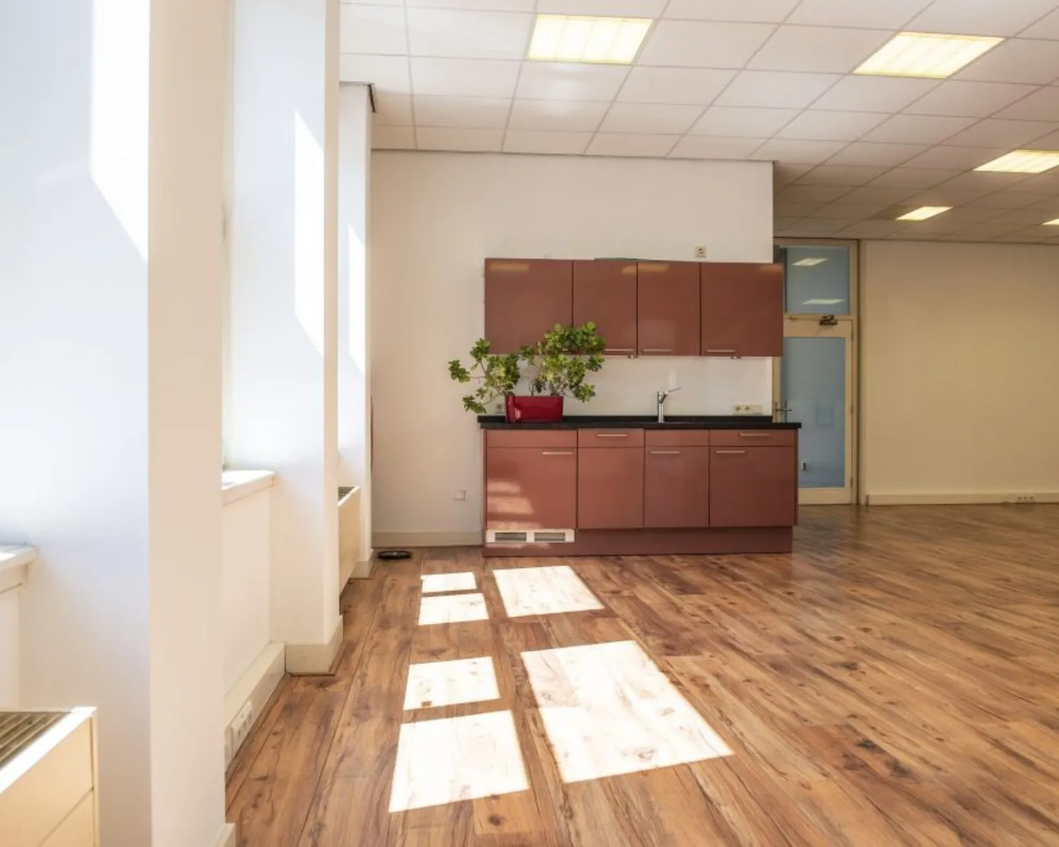 Lichte kantoorruimte aan de Wilhelminastraat 43A in Haarlem met houten vloer en kitchenette.