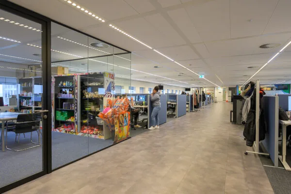 Modern kantoorinterieur aan het Weena met open werkplekken, glazen vergaderruimte en een kleurrijke snackhoek.