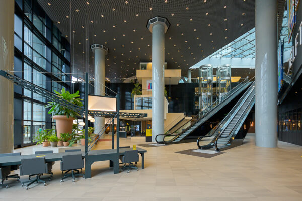 Moderne, ruime lobby van het kantoorgebouw aan het Weena met roltrappen, glazen liften en grote kolommen.