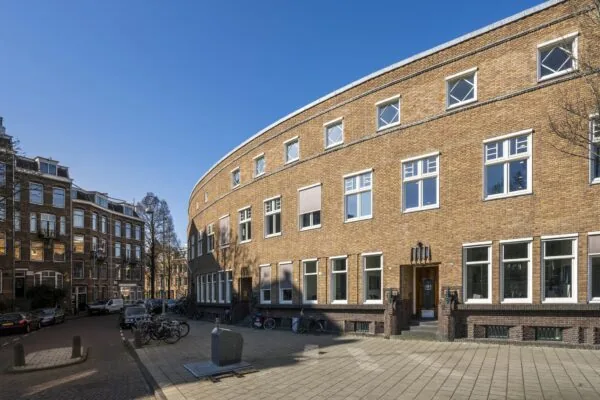 Gebogen bakstenen gevel van een woongebouw aan het Concertgebouwplein in Amsterdam op een zonnige dag.
