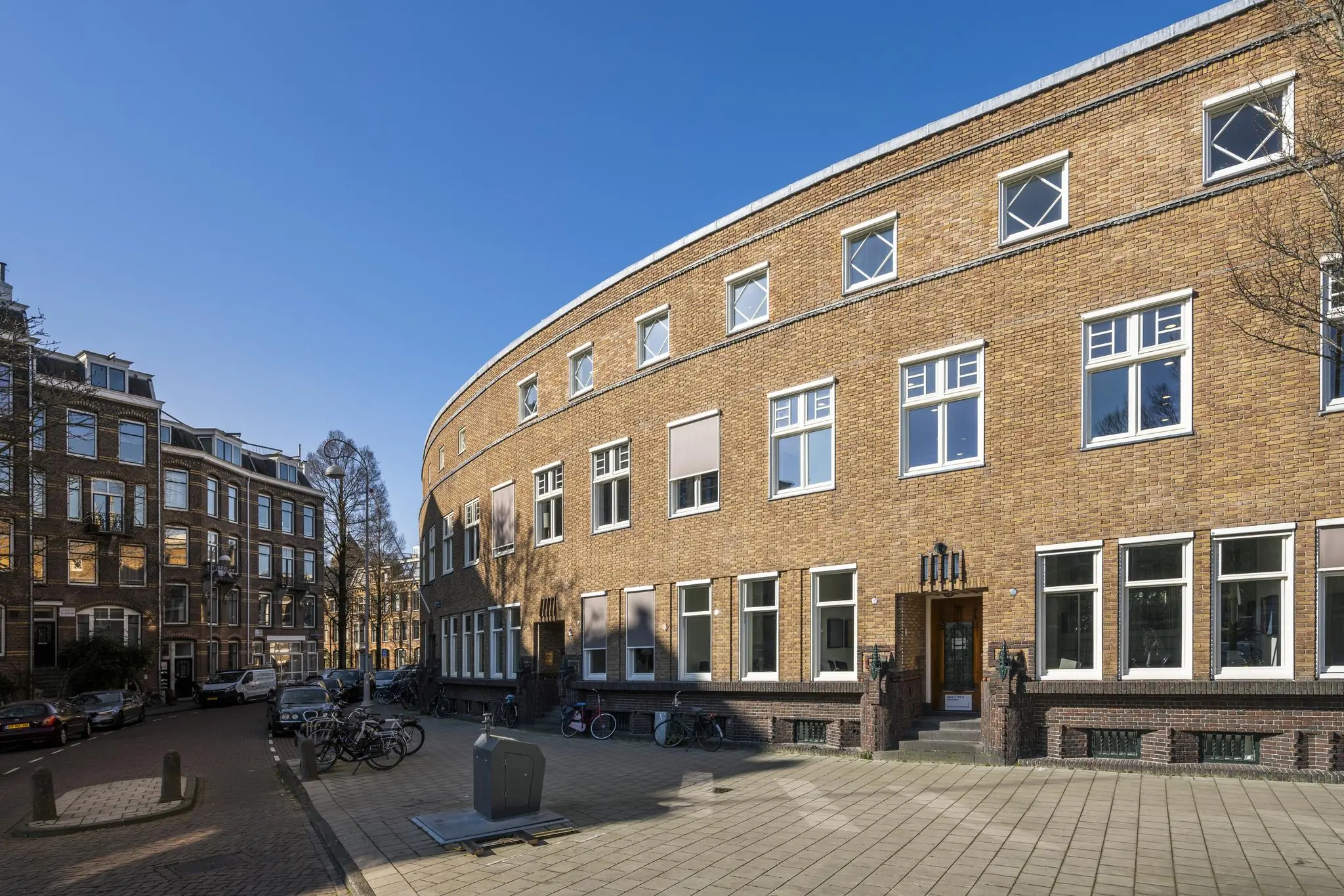 Gebogen bakstenen gevel van een woongebouw aan het Concertgebouwplein in Amsterdam op een zonnige dag.
