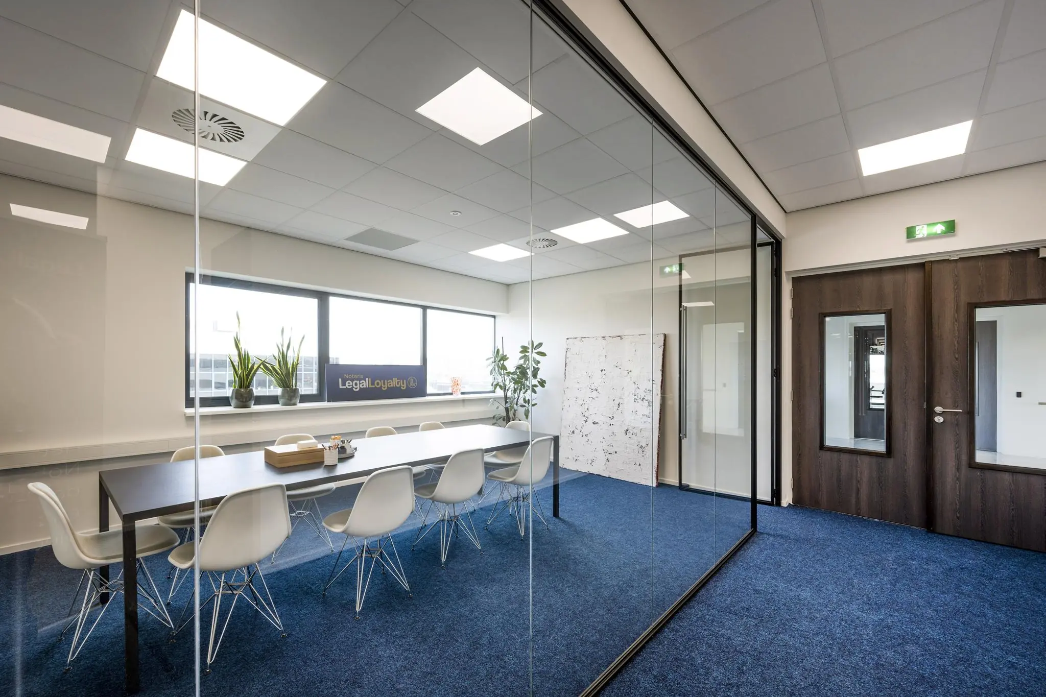 Moderne vergaderruimte van notaris LegalLoyalty aan de Dynamostraat met glazen wand, lange tafel en witte stoelen.