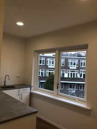 Keukenhoek met aanrecht en uitzicht op woonhuizen aan het Concertgebouwplein.