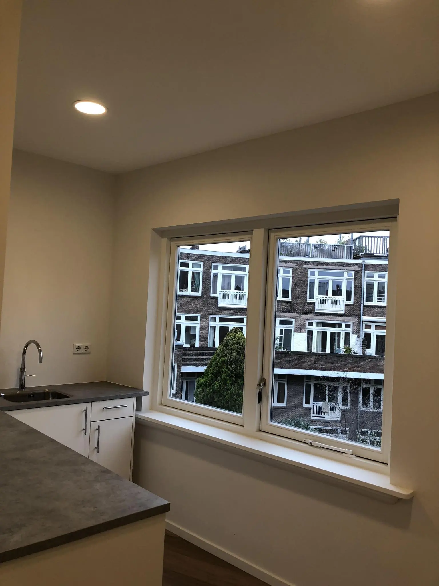 Keukenhoek met aanrecht en uitzicht op woonhuizen aan het Concertgebouwplein.