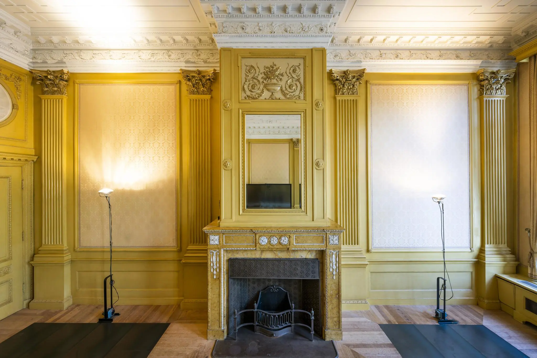 Historisch interieur van een statige kamer aan de Herengracht met rijk gedecoreerde schouw, wandpanelen en klassieke ornamenten.