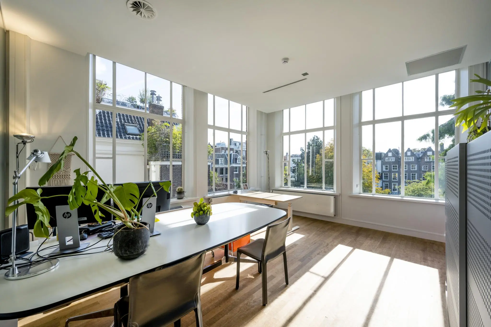 Licht en modern kantoorinterieur aan de Herengracht met grote ramen en uitzicht op grachtenpanden.