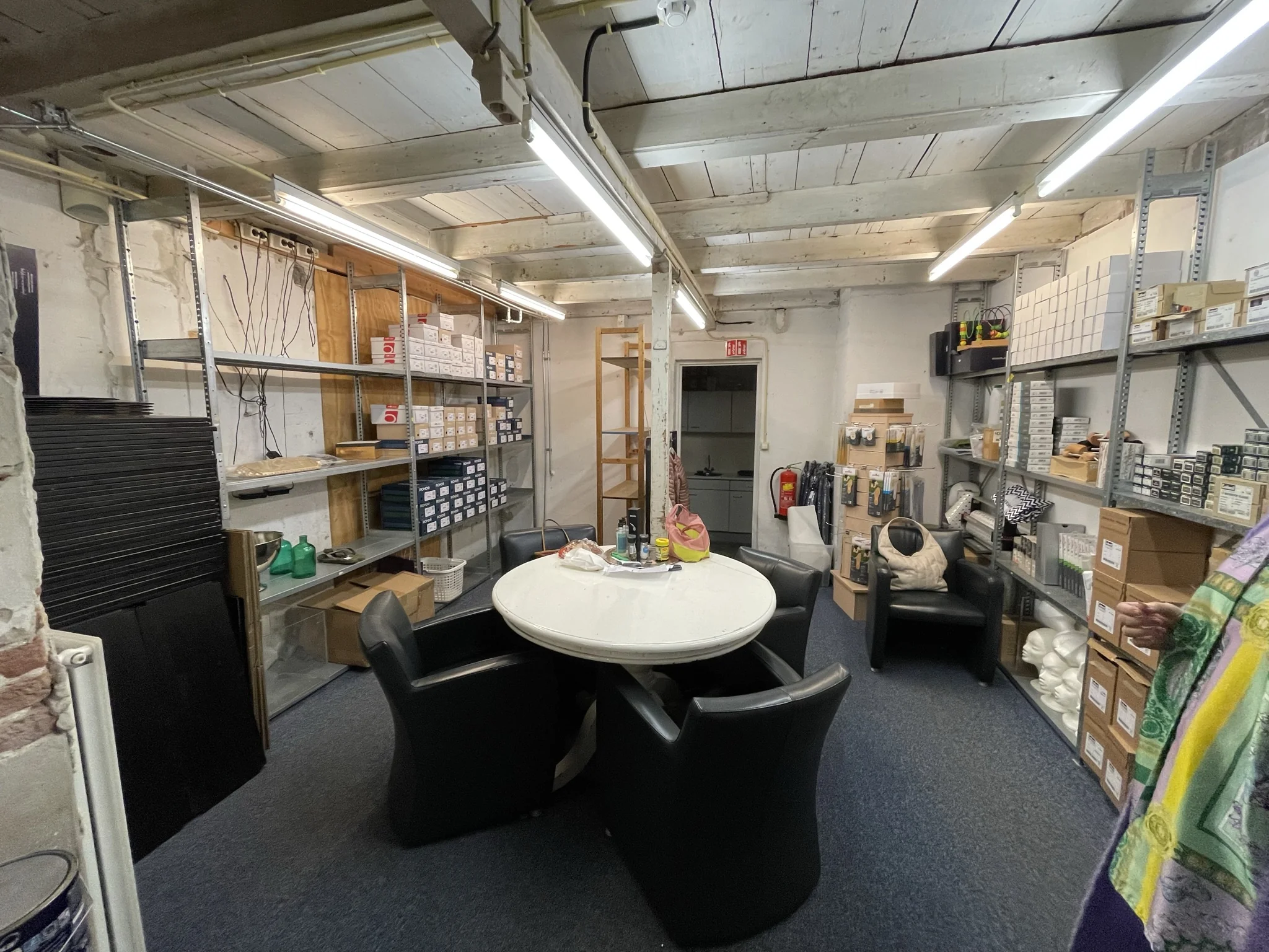 Opslagruimte aan de Molendijk met stellingen vol dozen en een ronde vergadertafel met stoelen.