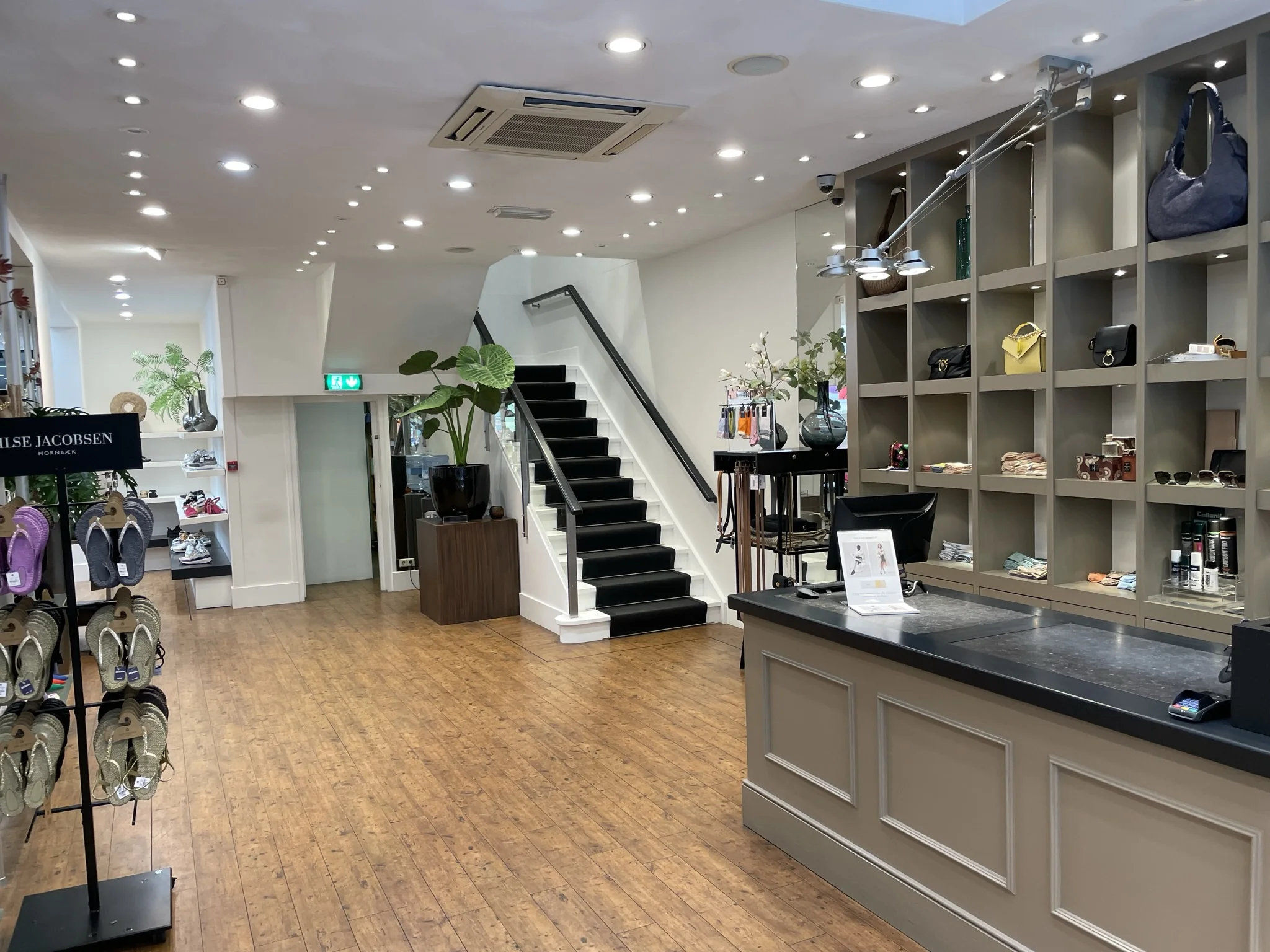 Luxe en moderne boetiek aan de Molendijk met een houten vloer, een toonbank, displays met accessoires en een trap naar boven.