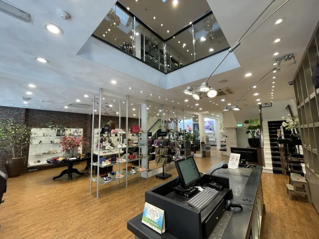 Alt-tekst: Moderne en stijlvolle schoenenwinkel aan de Molendijk met een open vide, houten vloer en overzichtelijke productpresentatie.