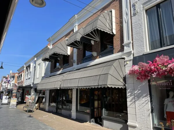 Winkelpand met zwarte zonneschermen aan de Molendijk op een zonnige dag.