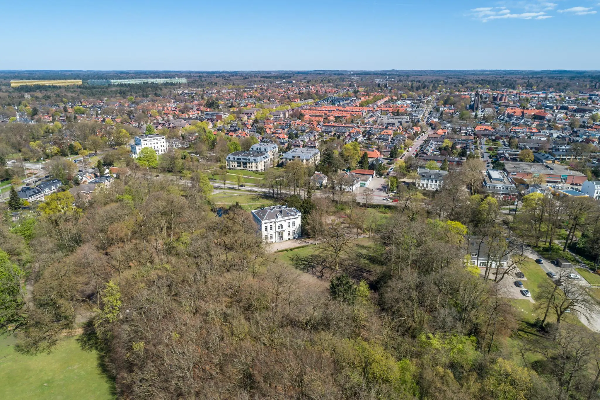 Luchtfoto van de Utrechtseweg in een groen, bebost gebied met zicht op gebouwen en woonwijken in Arnhem.