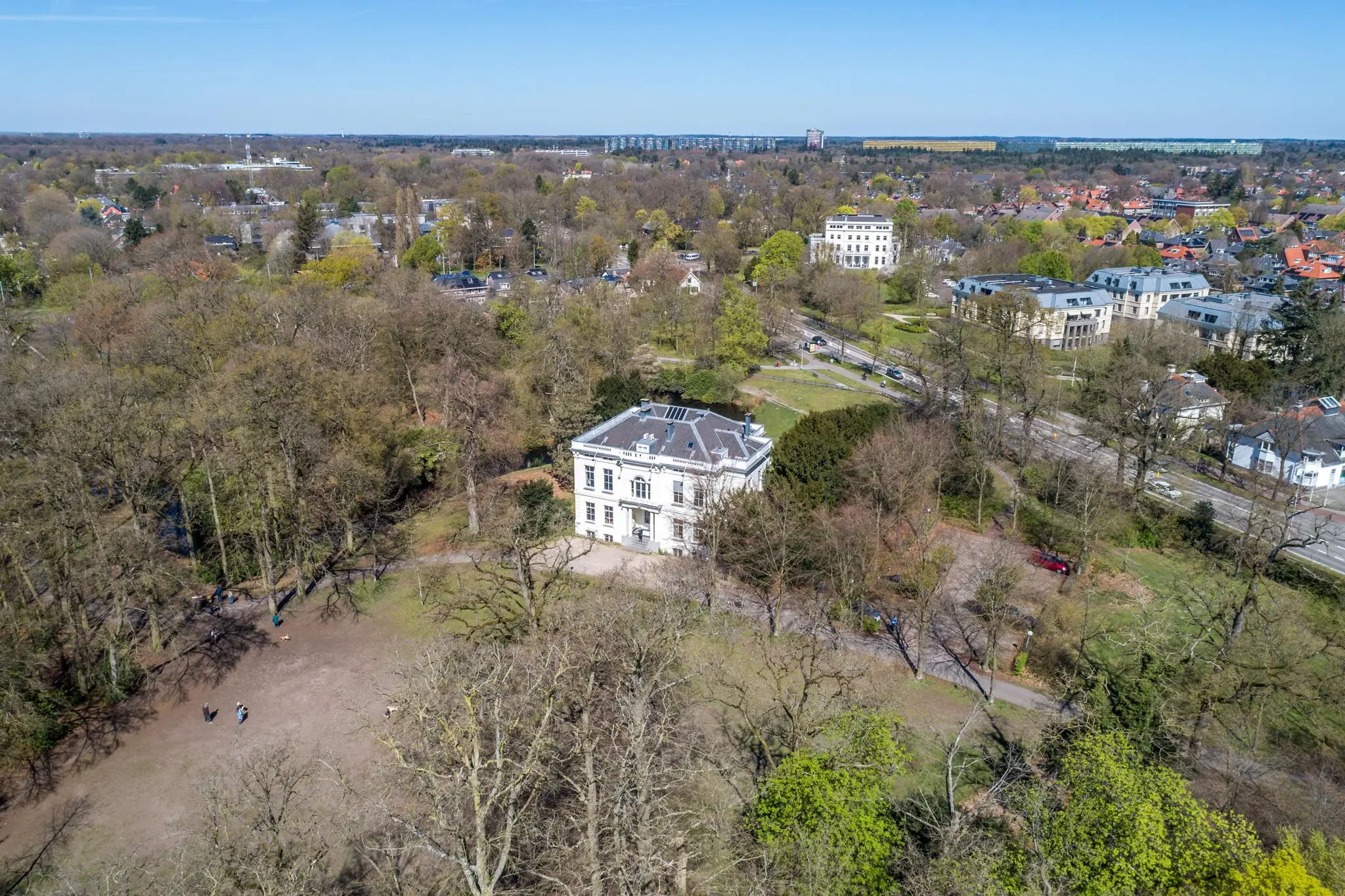 Luchtfoto van een wit herenhuis aan de Utrechtseweg in Arnhem, omgeven door bomen en stadsbebouwing.