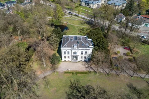 Luchtfoto van een wit herenhuis aan de Utrechtseweg in een groene, parkachtige omgeving.