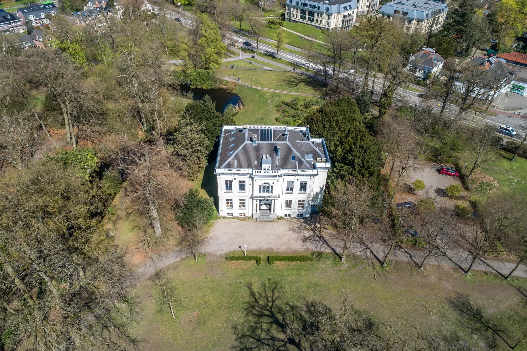 Luchtfoto van een wit herenhuis aan de Utrechtseweg in een groene, parkachtige omgeving.