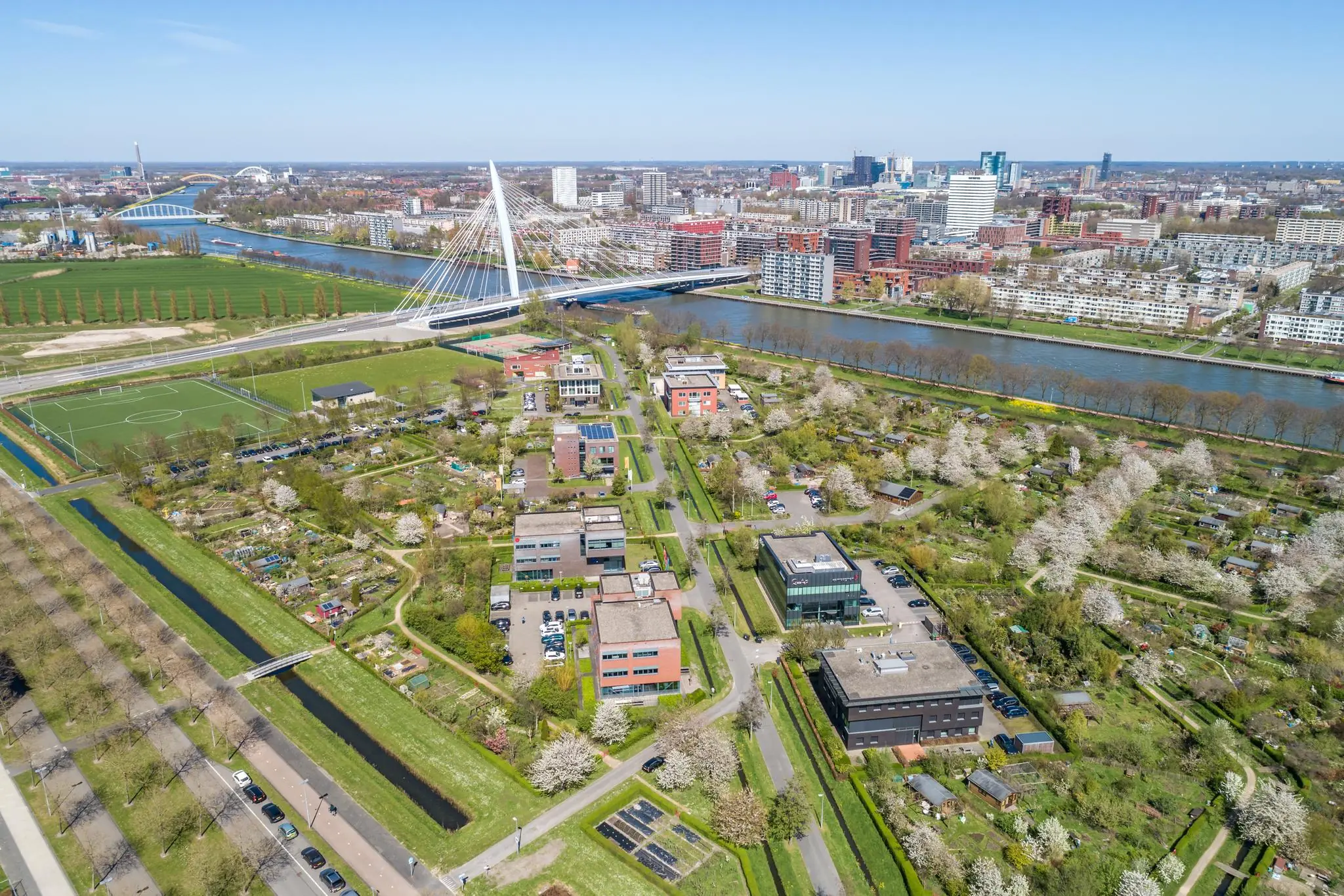 Luchtfoto van Groene Woudsedijk in Utrecht met kantoren, volkstuinen, sportvelden en de opvallende Daphne Schippersbrug over het Amsterdam-Rijnkanaal.