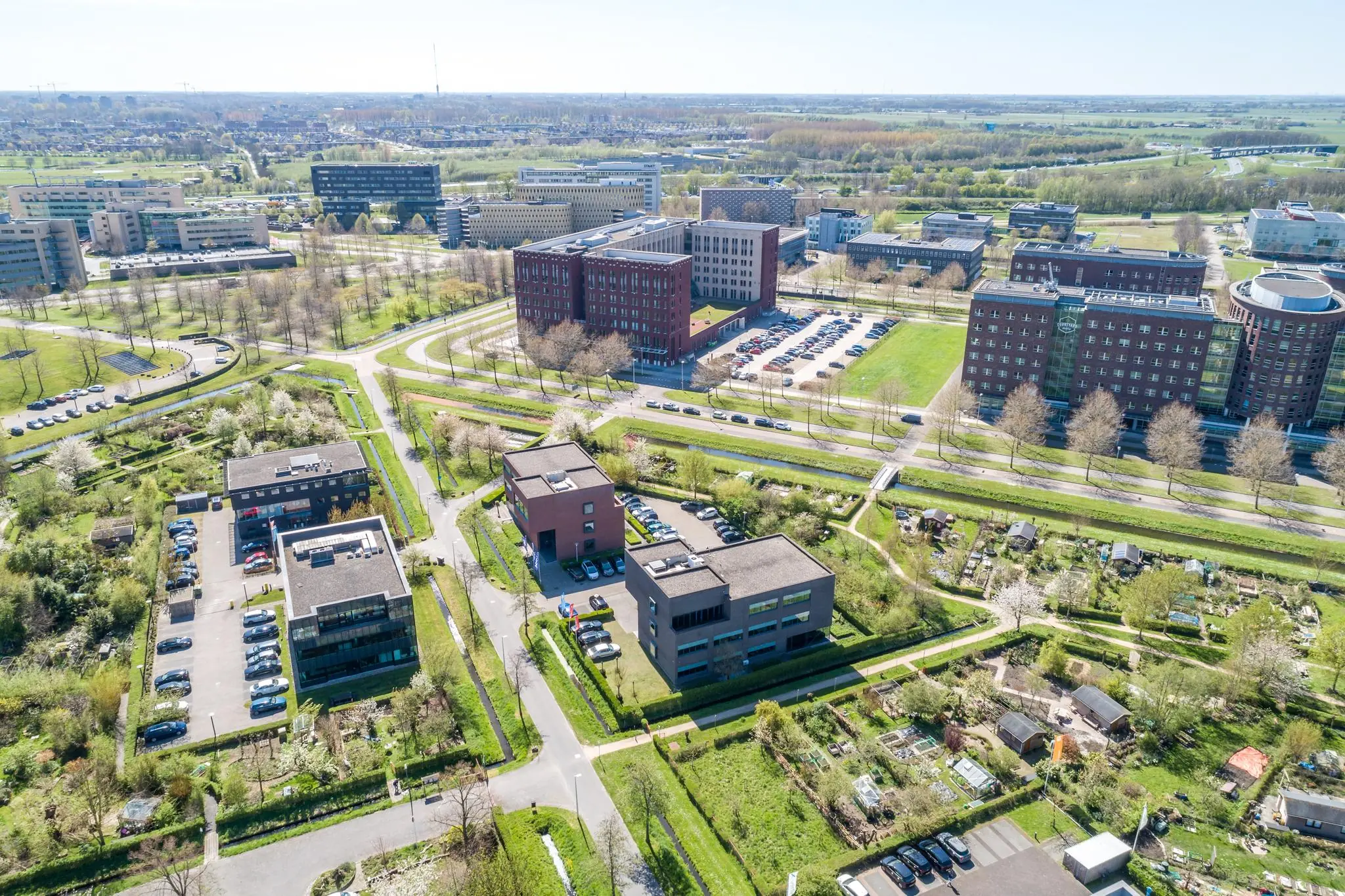 Luchtfoto van kantoren en volkstuinen aan de Groenewoudsedijk in een groen stedelijk gebied.