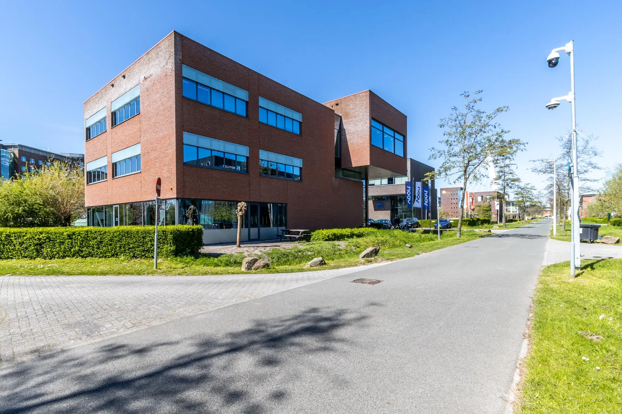 Kantoorgebouw aan de Groenewoudsedijk met modern bakstenen ontwerp en omliggend groen op een zonnige dag.