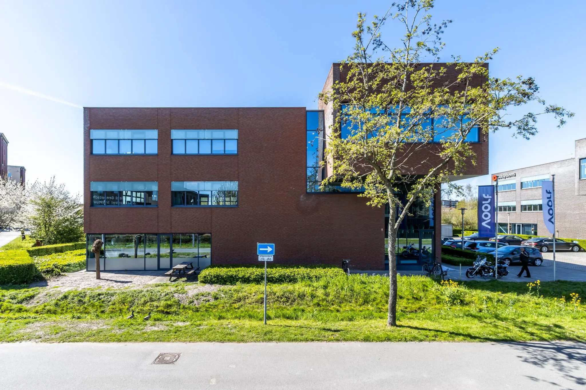 Modern kantoorpand aan de Groenewoudsedijk met bakstenen gevel, grote ramen en een parkeerterrein met vlaggen van bedrijf 4Dot.