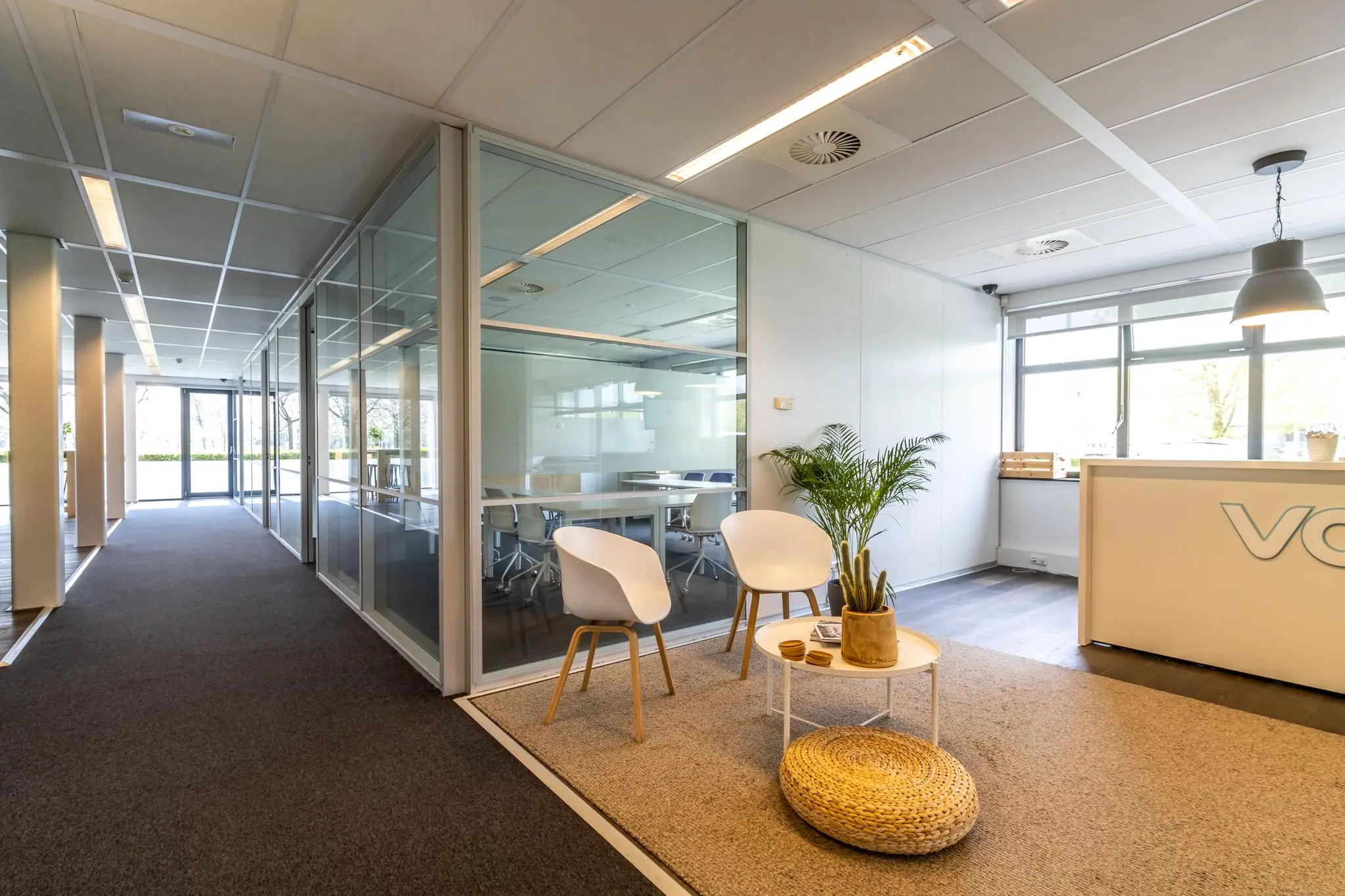 Moderne en lichte kantoorruimte aan de Groenewoudsedijk met glazen vergaderruimtes en een sfeervolle wachthoek.