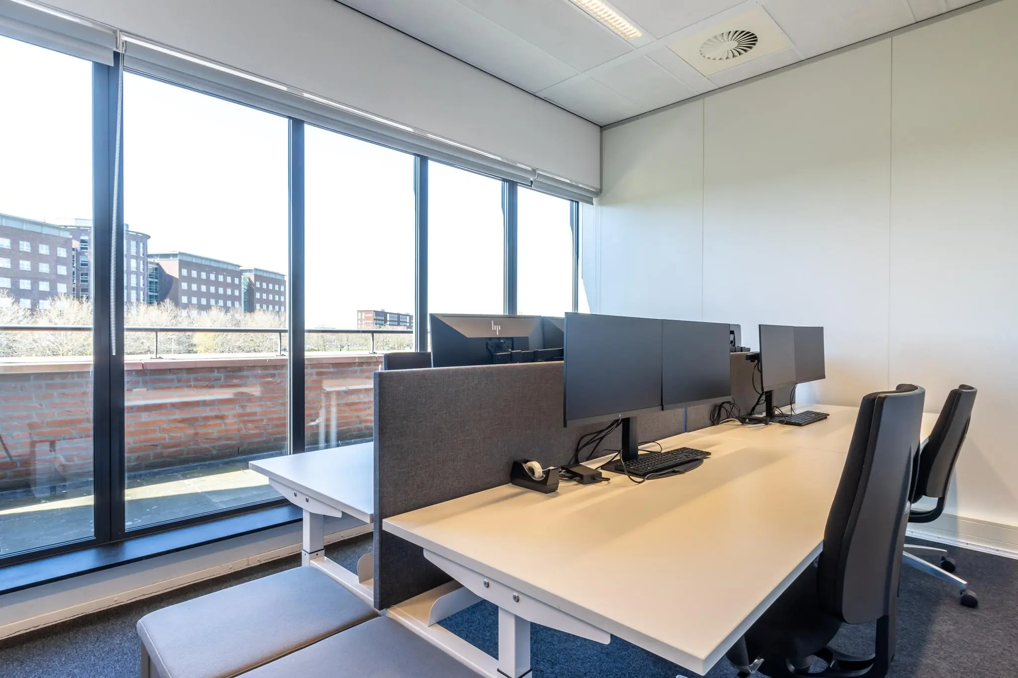 Modern kantoor met werkplekken en uitzicht op gebouwen aan de Groenewoudsedijk.
