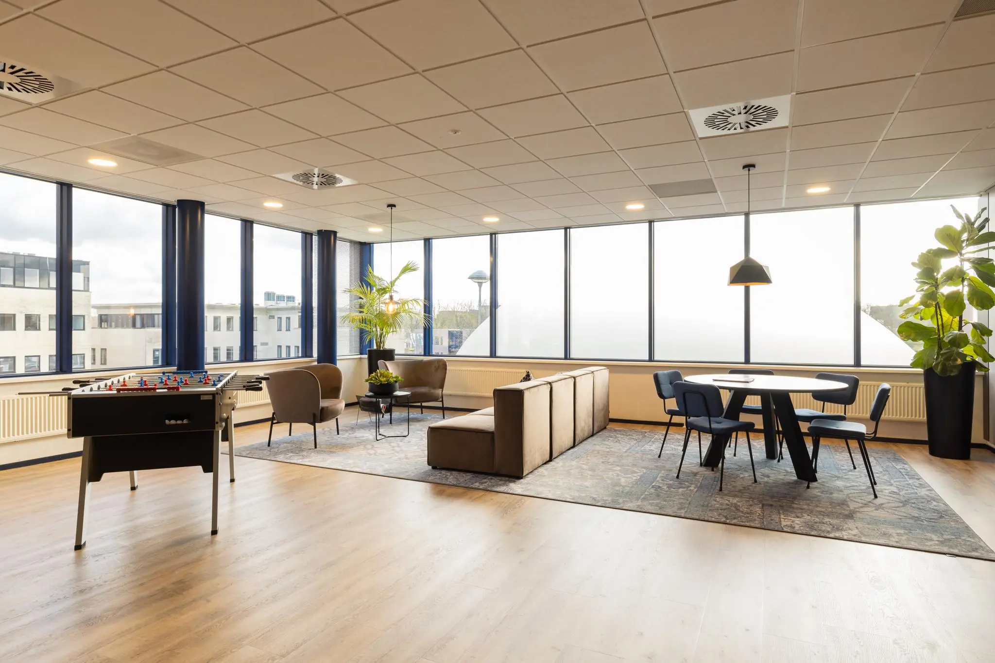 Moderne bedrijfsruimte aan de Fokkerstraat met zithoek, vergadertafel en tafelvoetbaltafel.