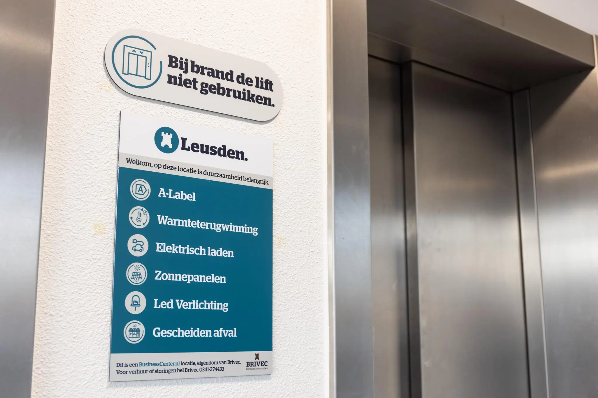 Informatieborden over duurzaamheid en veiligheid bij een lift in een gebouw aan de Fokkerstraat in Leusden.