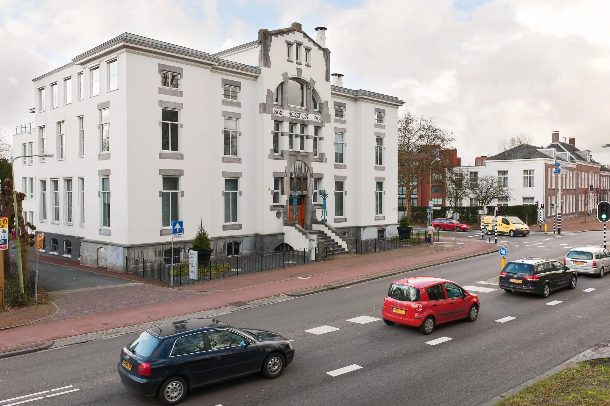 Wit historisch gebouw aan de Driebergseweg in Zeist met rijdend verkeer op de voorgrond.