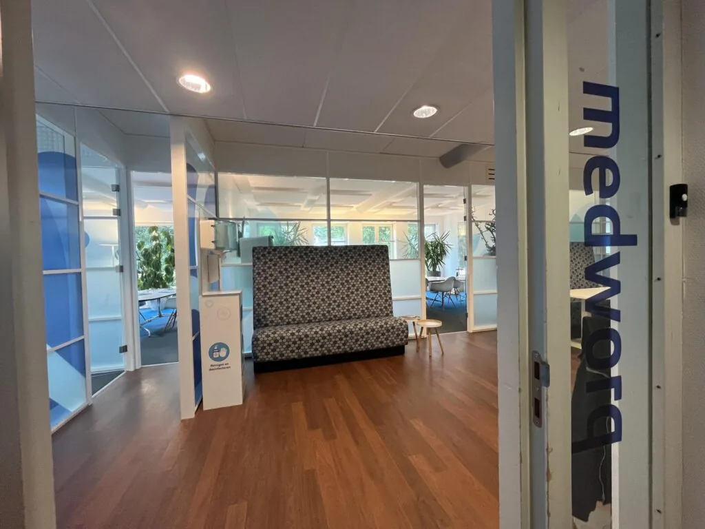 Ingang van een modern kantoor aan de Driebergseweg met zicht op een wachtruimte en glazen vergaderruimtes.