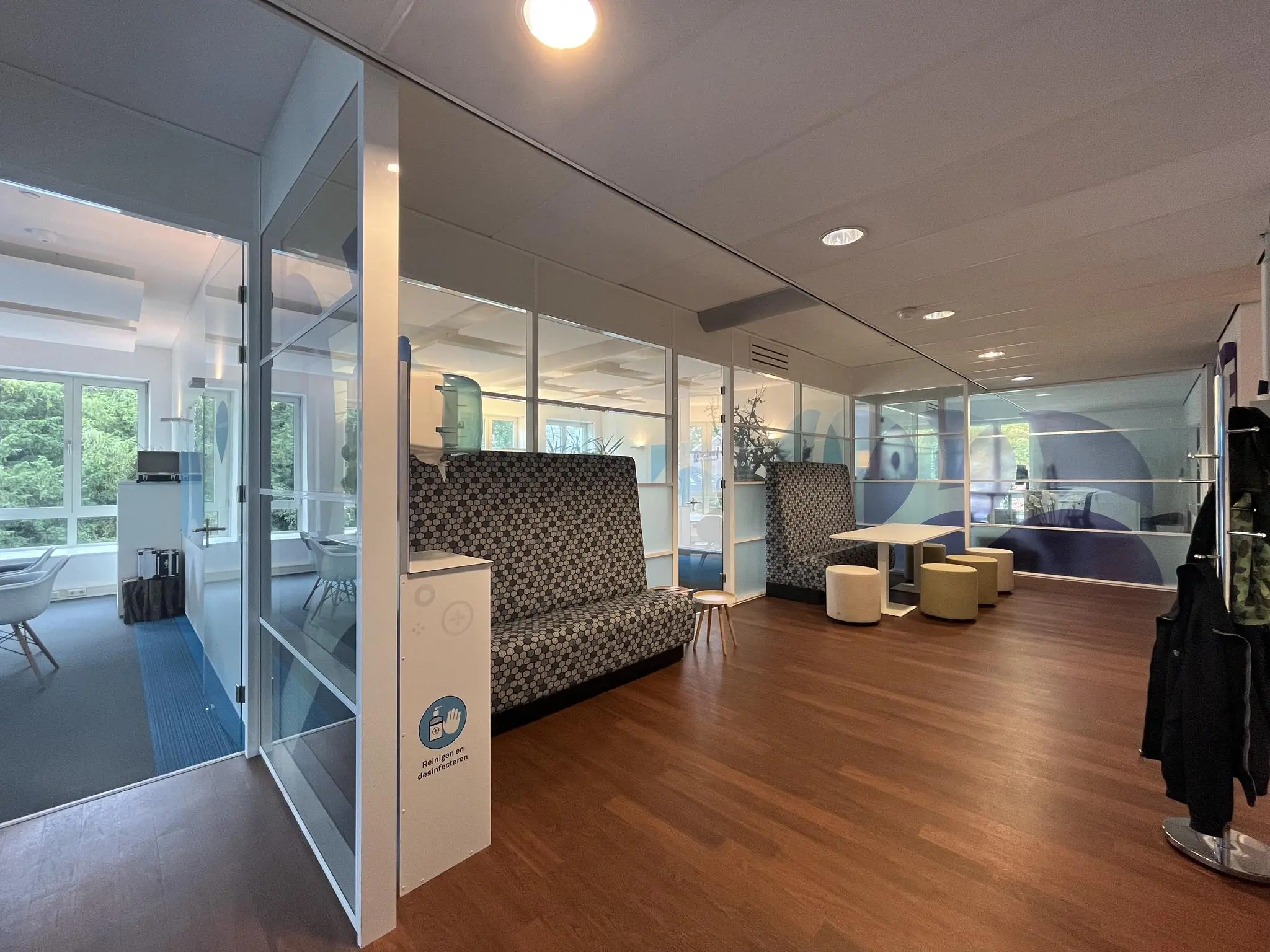 Moderne kantoorruimte aan de Driebergseweg met glazen vergaderruimtes, zitbanken en houten vloer.