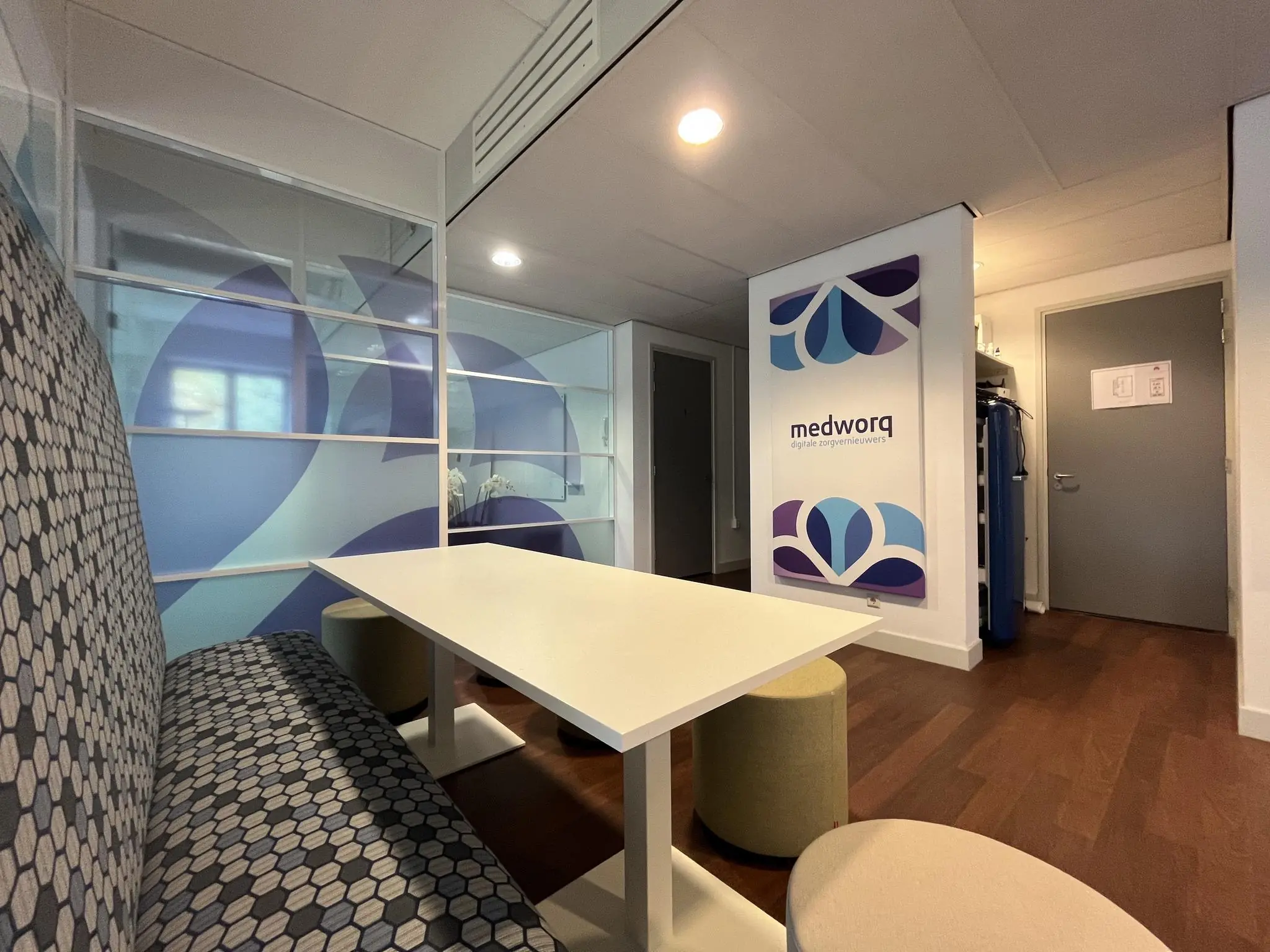 Moderne wachtruimte of spreekruimte bij Medworq met kleurrijk glasdesign en zithoeken.