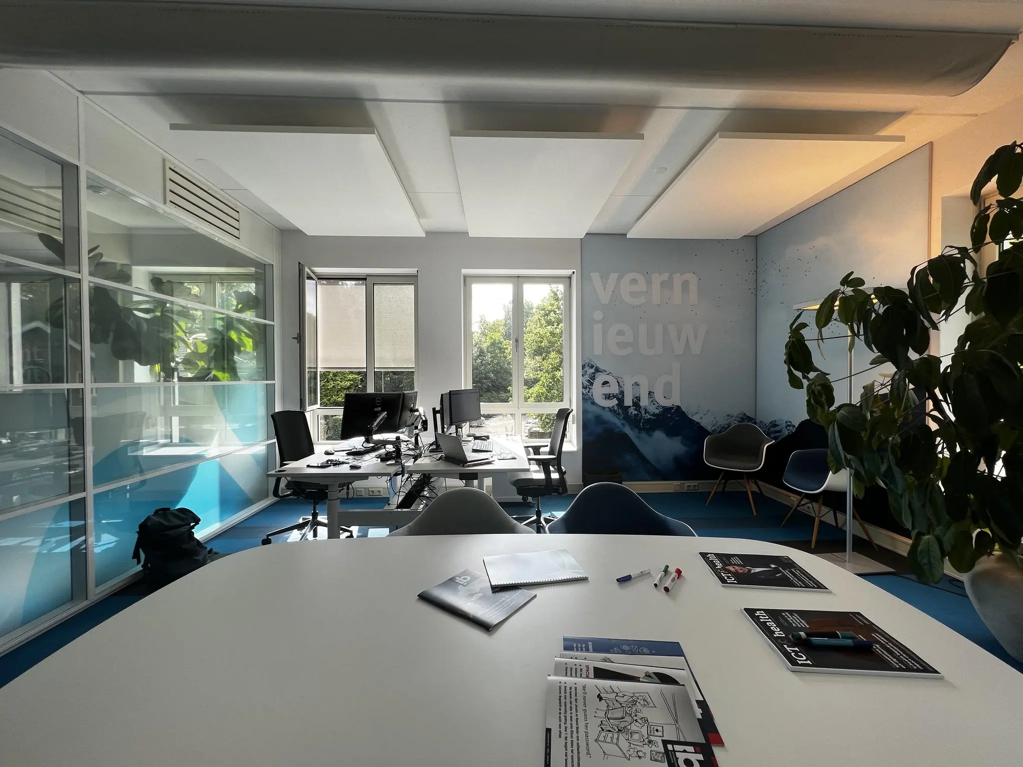 Moderne kantoorruimte aan de Driebergseweg met werkplekken, vergadertafel en een muur met de tekst "vernieuwend".
