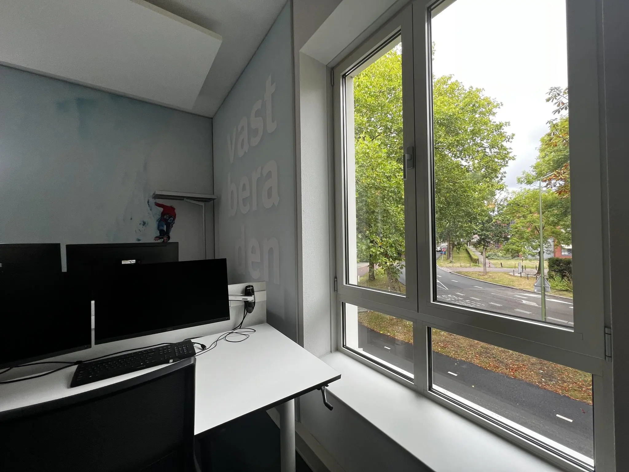 Kantoorruimte met werkplek en uitzicht op de Driebergseweg door een groot raam.