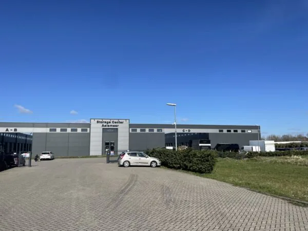 Grijs bedrijfsgebouw met de naam "Storage Center Aalsmeer", gelegen aan de Aalsmeerderweg, met geparkeerde auto's op de voorgrond.