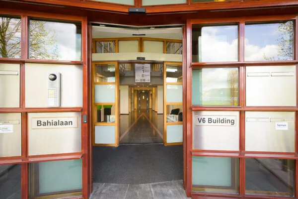 Ingang van het V6-gebouw aan de Bahialaan met zicht op de centrale gang binnenin.