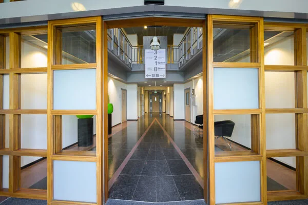 Ingang van een modern kantoorgebouw aan de Bahialaan met glazen deuren en een strakke, brede hal.