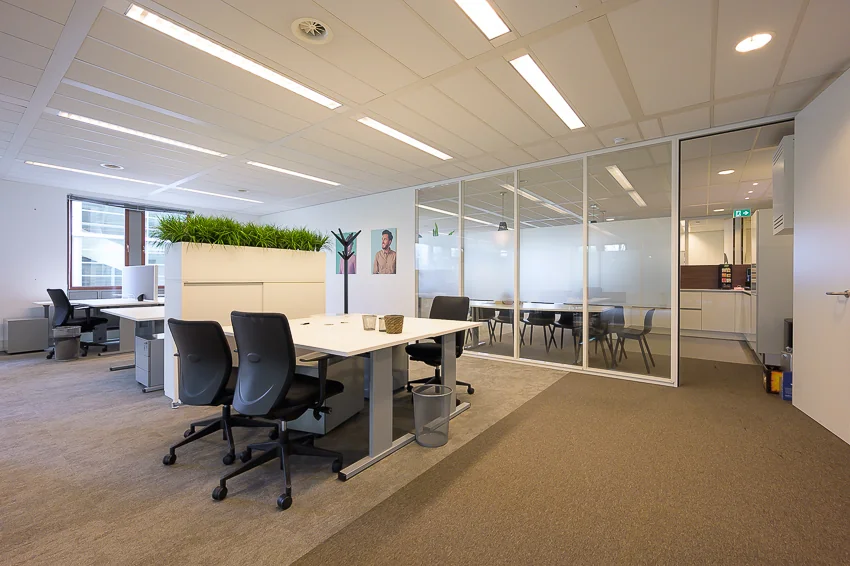 Modern kantoorinterieur aan de Bahialaan met flexplekken, vergaderruimte en groene scheidingswand.