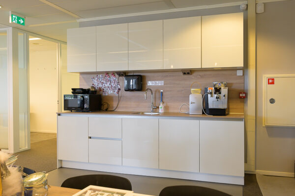 Moderne kantoorpantry aan de Bahialaan met witte kasten, koffieapparaat, magnetron en spoelbak.