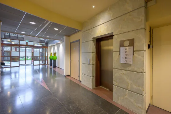 Moderne entreehal aan de Bahialaan met een lift, glazen toegangsdeuren en strakke afwerking.