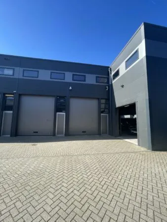 Moderne bedrijvenspand met grijze gevel en meerdere garage- en loopdeuren aan de Aalsmeerderweg.